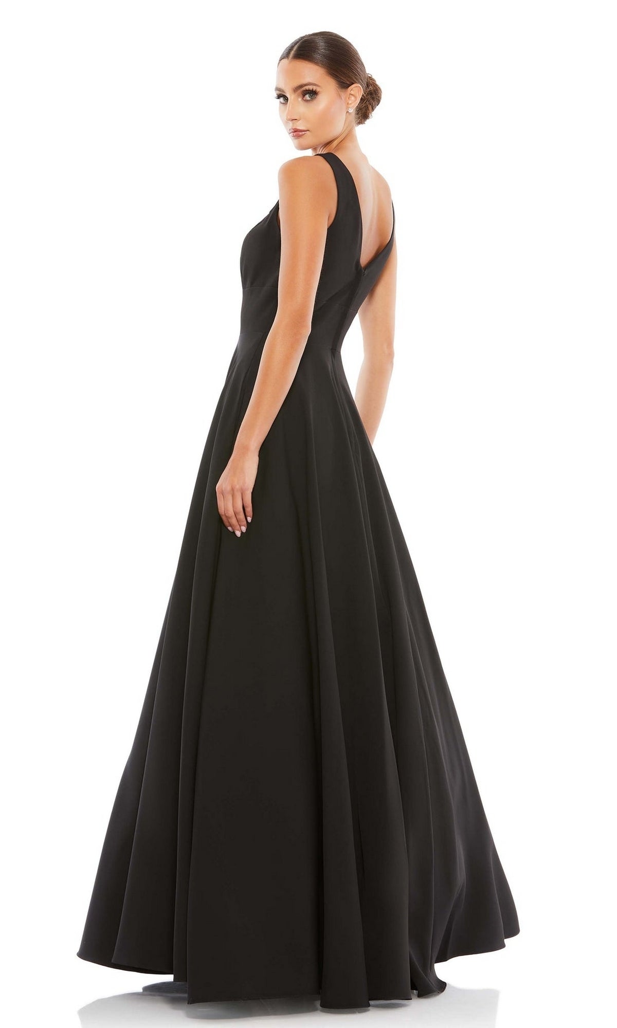 A woman poses in the Classic Long Prom Ball Gown: Mac Duggal 48924, a full-length sleeveless black dress with an A-line silhouette, glancing over her shoulder against a white background.